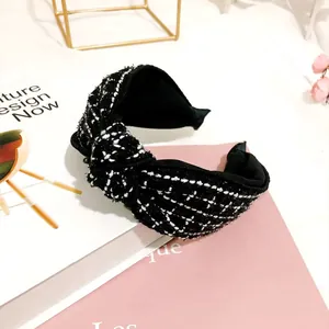 Dettaglio del cerchietto annodato in tweed bianco e nero dal design retrò elegante