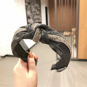 Dettaglio di fascia per capelli in organza a pois neri con nodo e strass