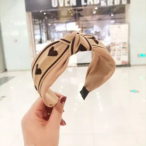 Gros plan sur un bandeau tricoté beige noué avec un motif de cœur marron élégant