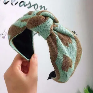 Close-up of a stylish knitted wide-band headband with a knot and mint green pattern.