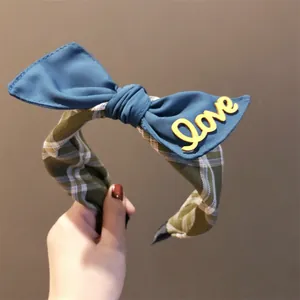 Detailopname van een blauwe strik haarband met gele Love-letters en groene ruit