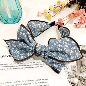 Close-up of vintage blue floral bow headband with brown piping on white background
