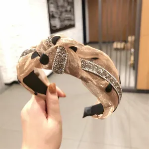 Dettaglio di un cerchietto con strass scintillanti e tessuto organza a pois
