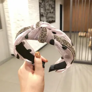 Dettaglio ravvicinato di un cerchietto in organza a pois rosa con accenti di strass lucidi.