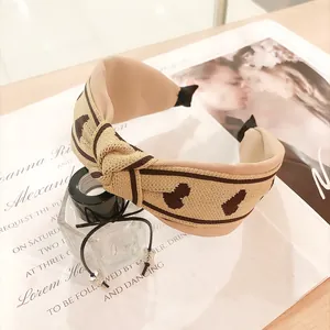 Gros plan d'un bandeau large en tricot beige avec nœud pour femme dans un décor élégant.