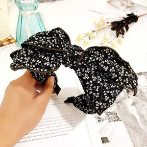 Close-up of a vintage black floral bow headband for women featuring an elegant retro design