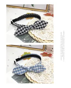 Detailed view of two gingham bunny ear headbands in black and blue on a straw mat background.
