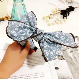 Vintage floral print large bow headband held in hand for detail showing fabric texture