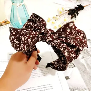 Detail view of a large vintage floral print bow headband featuring a wide non-slip band.