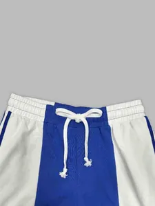 Close-up of the waistband on blue and white color-block sports pants with a white drawstring.
