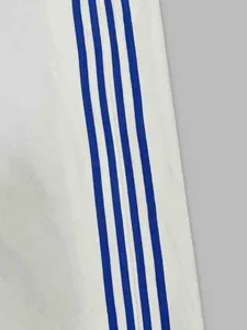 Detailed macro shot of three blue side stripes on white retro sport tracksuit pants
