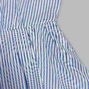 Detalle de cerca de un vestido camisero a rayas azules y blancas con bolsillo lateral