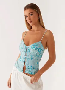 Detailed view of light blue sequined camisole with floral embroidery and tie-front.