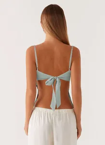 Back view of a light blue sequin camisole top featuring a stylish tie-back bow detail.