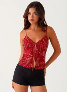 Front view detail of a red sequined camisole with deep V-neck and delicate tie closure.