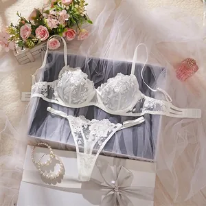 Detailed view of white rose embroidered sheer lingerie set on romantic gift setup
