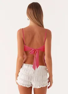 Back view of pink sequined camisole top featuring an elegant ribbon tie-back detail.