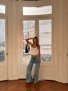 Full body shot of a model wearing a chic polka dot camisole with wide leg denim jeans