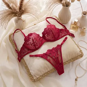 Detailed macro view of red lace lingerie set with floral embroidery placed on a soft pillow