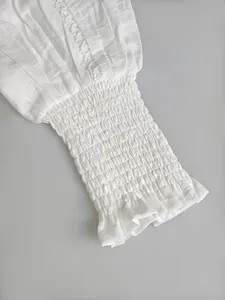 Close-up of white lantern sleeve with smocked cuff and delicate lace detail