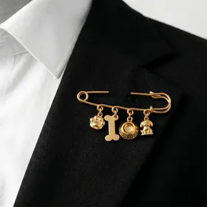 Détail d'une broche en acier titane doré avec breloques de chien sur un revers noir.