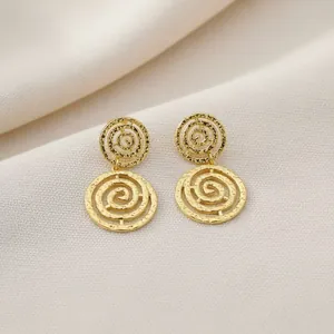 Detailansicht goldener Ohrhänger mit Spiralausschnitt und Hammerschlag-Textur.