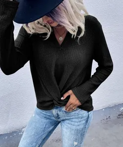 Close-up detail of black waffle knit long sleeve top featuring a chic twist knot hem
