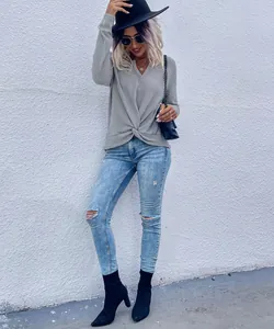 Stylish grey V-neck knit top with unique front twist knot detail worn by a fashion model