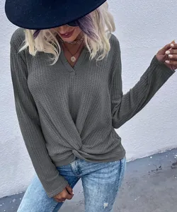 Detailed view of gray waffle-knit long-sleeve top featuring a stylish twist-knot detail at the hem