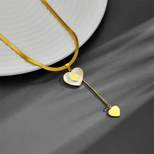 Dettaglio di una collana a catena serpente in acciaio dorato con nappa a cuore in conchiglia.