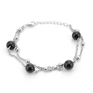 Vista detallada de una pulsera de plata de dos hilos con cuentas negras y cierre de mosquetón