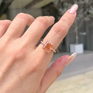 Detailed close-up of a radiant cut orange gemstone ring on a finger with micro-pave band