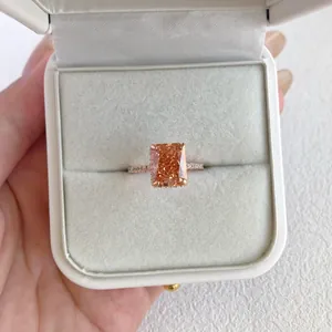 Detailed view of a sparkling orange radiant-cut zirconia ring in a white jewelry gift box