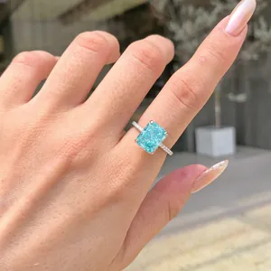 Close-up of a sterling silver ring with a radiant cut cyan zircon on a hand