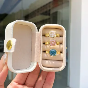 Juego de tres lujosos anillos de circonita en blanco rosa y azul en un joyero portátil