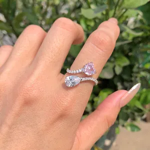 Vista detallada de anillo de plata S925 con corazón rosa y circón pera en la mano