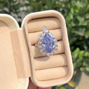 Detalle de un anillo con circón azul en forma de pera en un joyero de terciopelo beige.