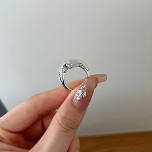 Detailed macro view of S925 sterling silver heart ring with sparkling stones on hand.