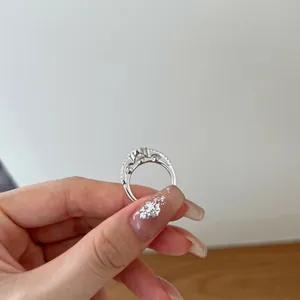 Close-up view of a silver S925 heart ring with zircons, side profile held by hand.