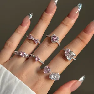 Primer plano de anillos de plata con corazones y circonitas rosas en mano cuidada