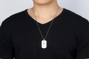 Primo piano dettagliato di una collana con piastrina in acciaio indossata da un modello in nero.