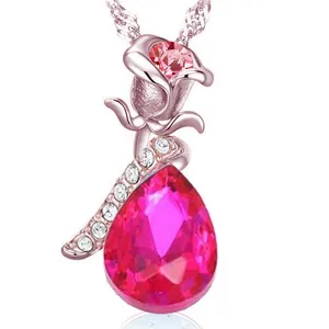 Primo piano di un elegante pendente a rosa con un cristallo rosa a forma di goccia di pera.
