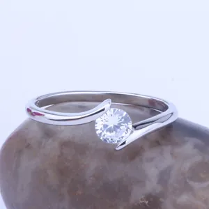 Detail view of silver-tone crossover ring featuring a brilliant round-cut zircon stone.