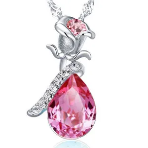 Dettaglio ravvicinato di un ciondolo a rosa e cristallo rosa a goccia su catena