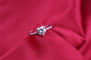 Exquisite silver heart-shaped ring featuring AAA zircon stones displayed on red fabric