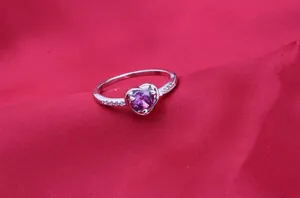 Close-up of heart-shaped ring with vibrant purple AAA zircon and side stones