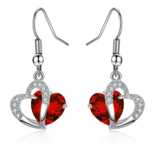 Detailed close-up of heart-shaped drop earrings with red faceted stones and plating
