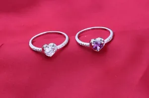 Detailed macro view of two AAA cubic zirconia heart-shaped rings in purple and white