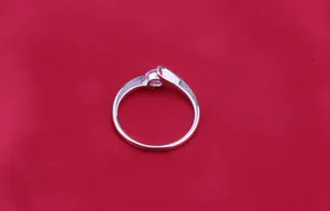 Silver bypass engagement ring with sparkling round cubic zirconia on red background