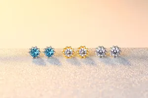Detailed view of crown-shaped stud earrings in three colors on a golden glitter surface